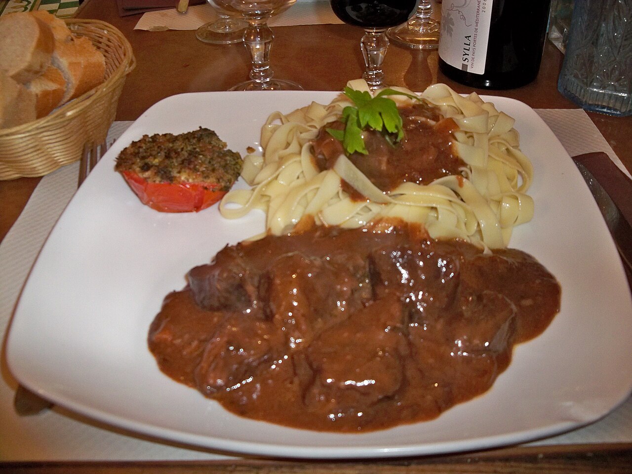 A plate of boeuf bourguignon, beef braised in red wine with carrots and onions