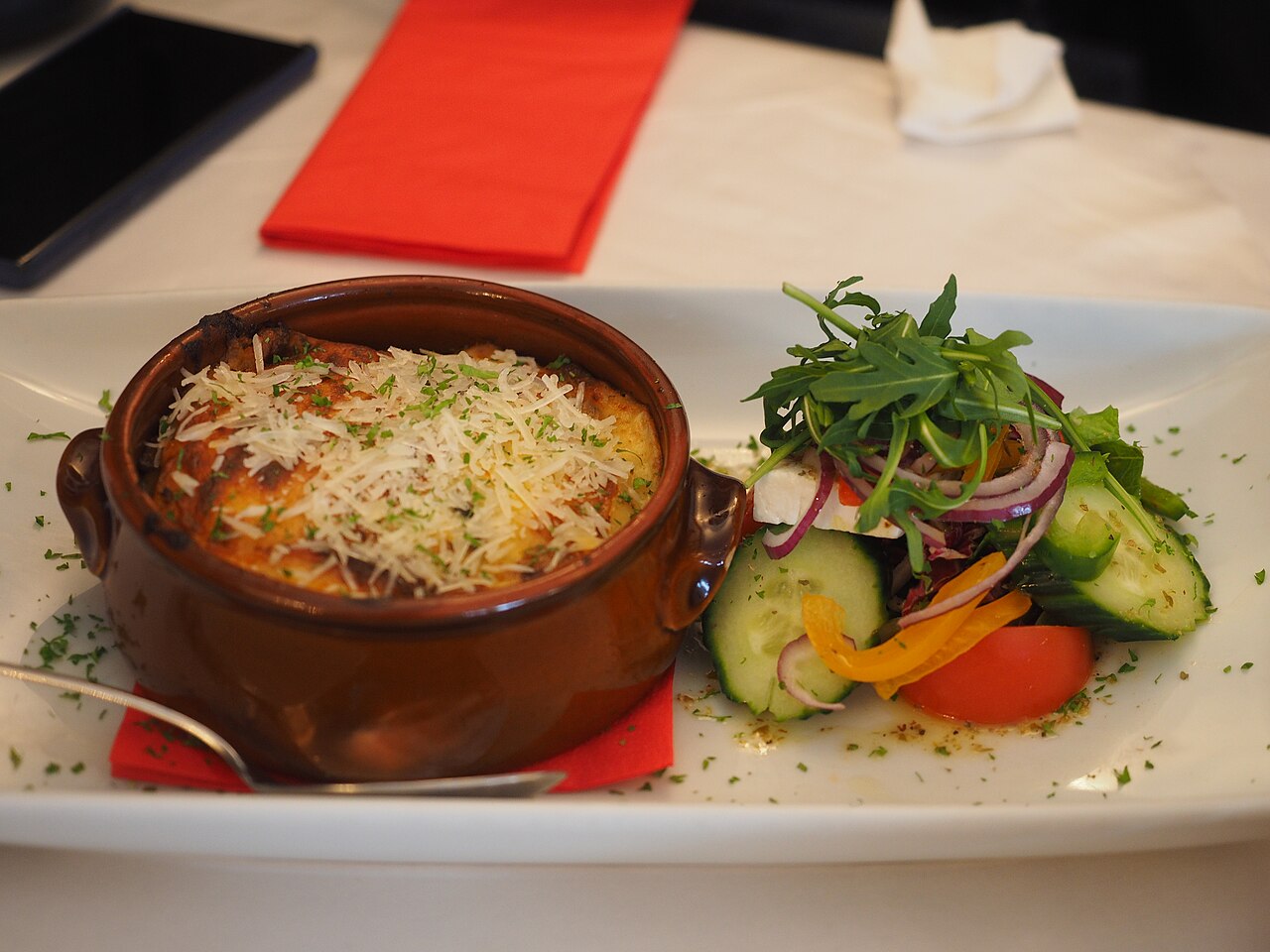 A baked dish of moussaka, layered aubergine and mince under a browned topping, served in a taverna