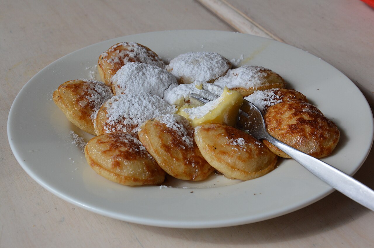 A plate of poffertjes, small puffed pancakes, dusted with icing sugar