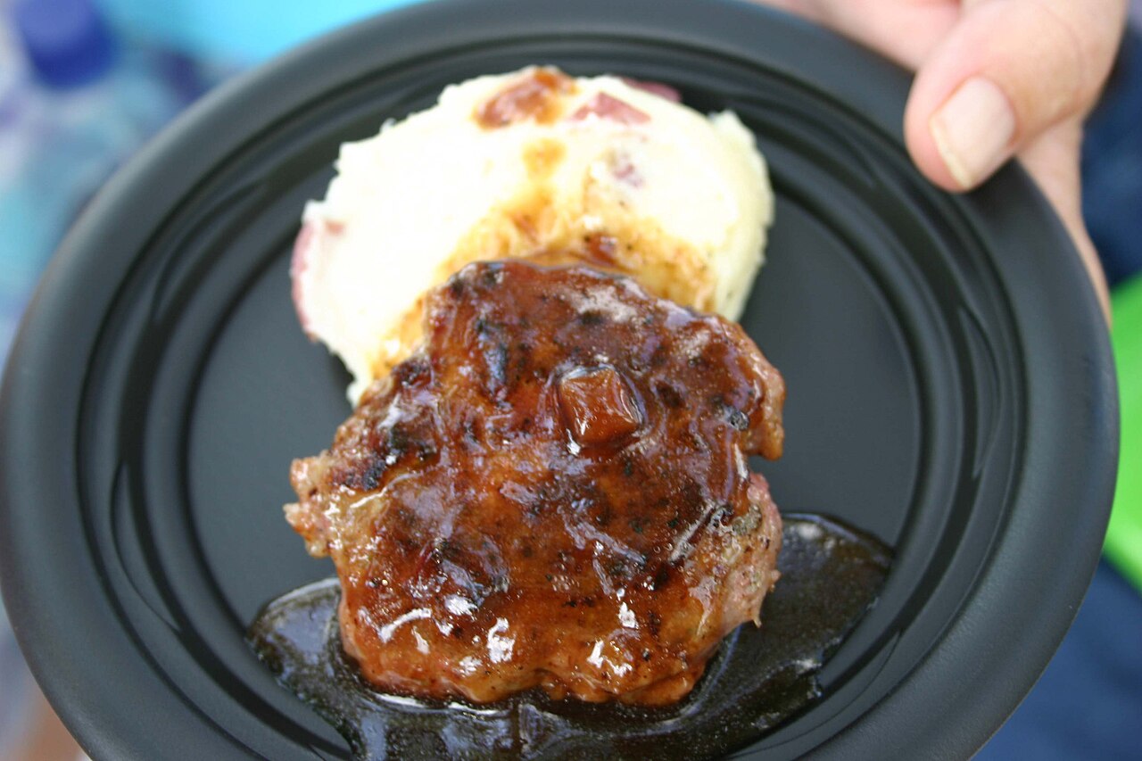 Norwegian meatball patties in brown gravy on a plate with potatoes, vegetables and lingonberry jam