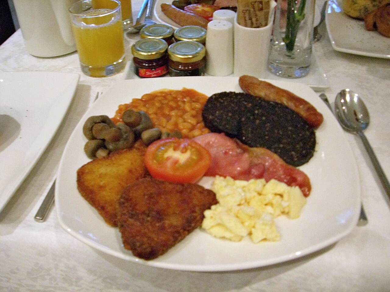 A full English breakfast on a plate with eggs, bacon, sausage, beans and toast