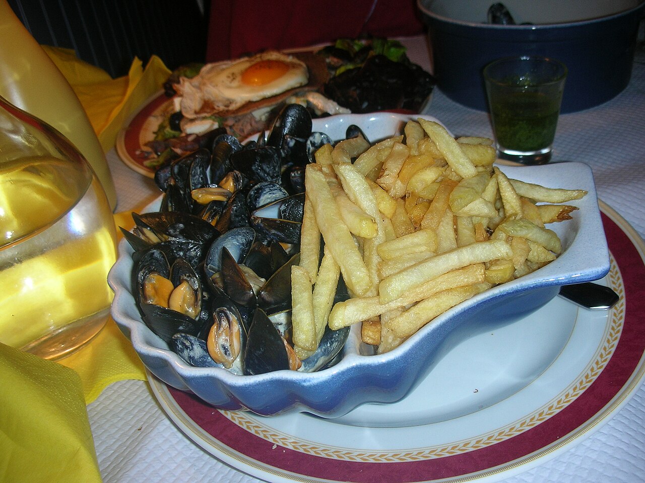 A pot of steamed mussels served with a portion of fries