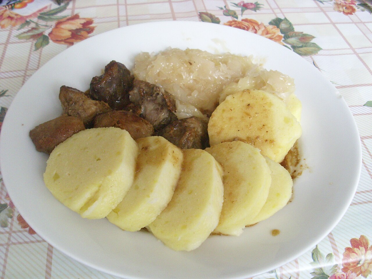 A plate of roast pork with sliced bread dumplings and sauerkraut