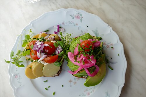 Open sandwiches of smørrebrød on rye bread with toppings, served on a table in Copenhagen