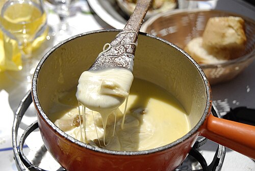 A pot of cheese fondue with cubes of bread