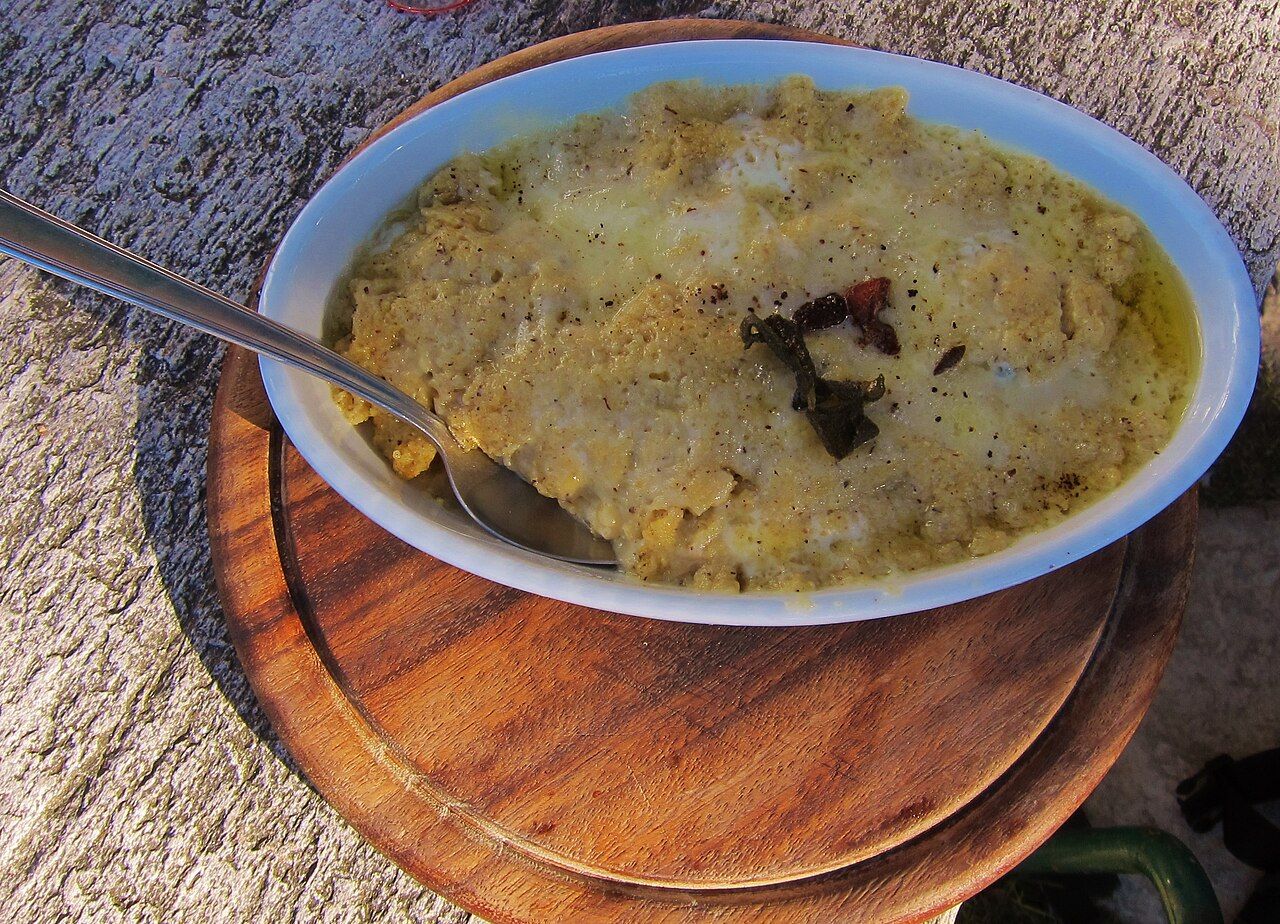 Polenta uncia, a baked dish of polenta with melted cheese and sage, in a white oval bowl