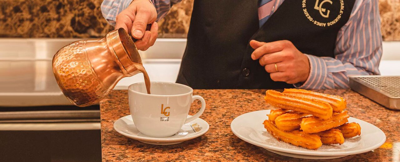 A plate of churros with a cup of thick hot chocolate