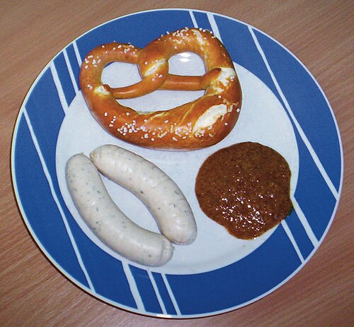 Weisswurst in a bowl with a pretzel and sweet mustard