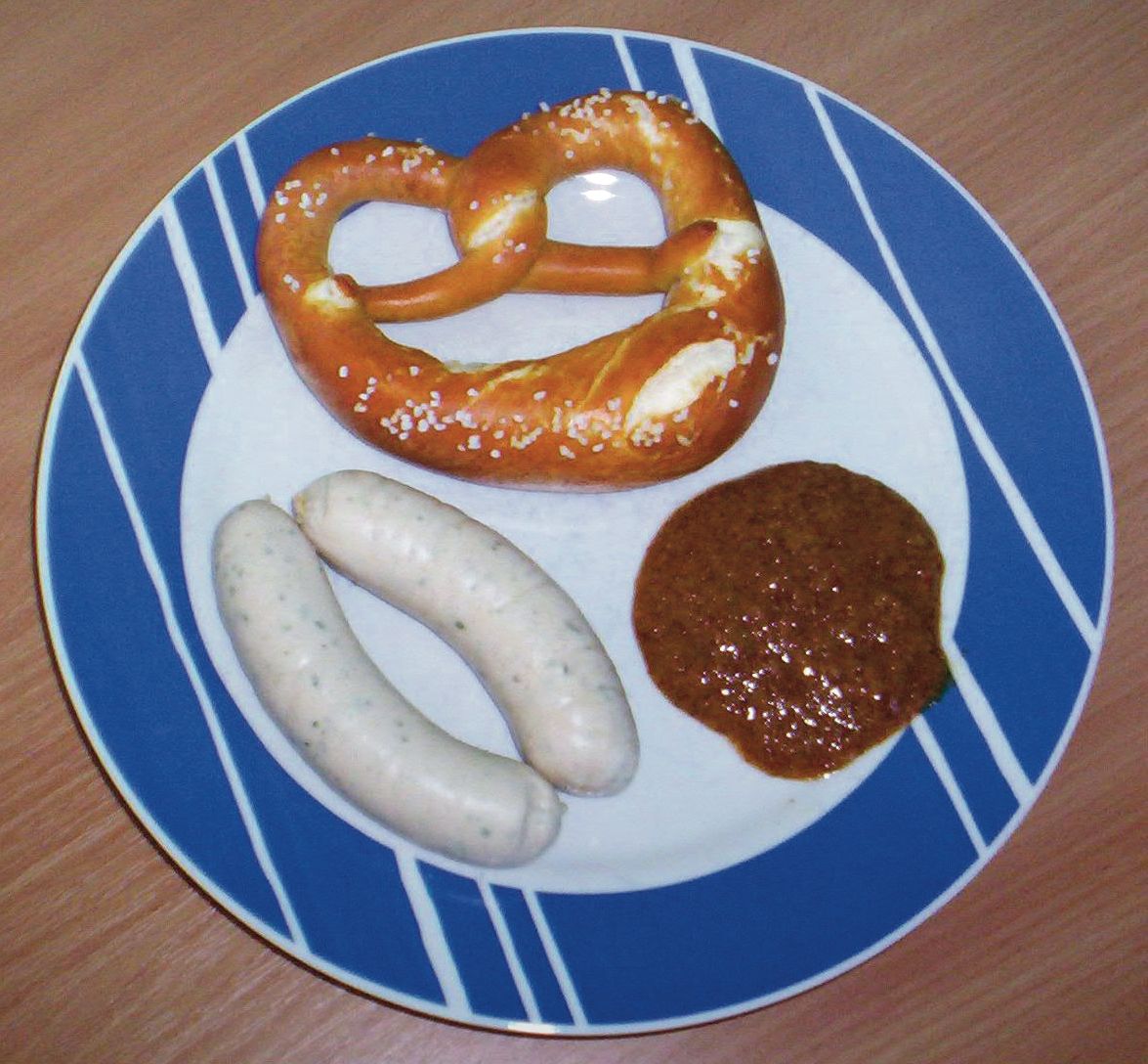 Weisswurst in a bowl with a pretzel and sweet mustard
