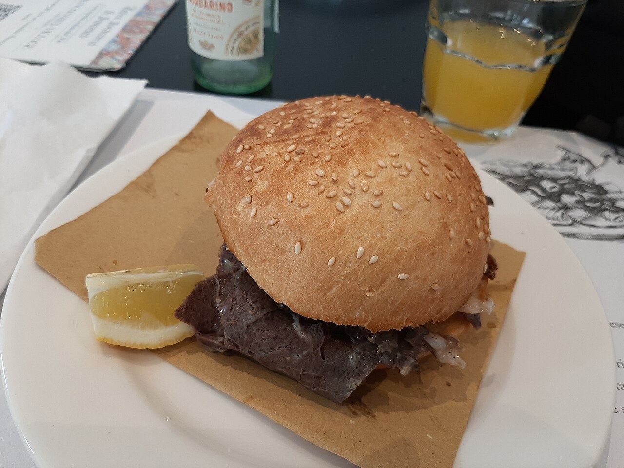 A pani ca meusa, a soft bread roll filled with sliced beef spleen, on a plate