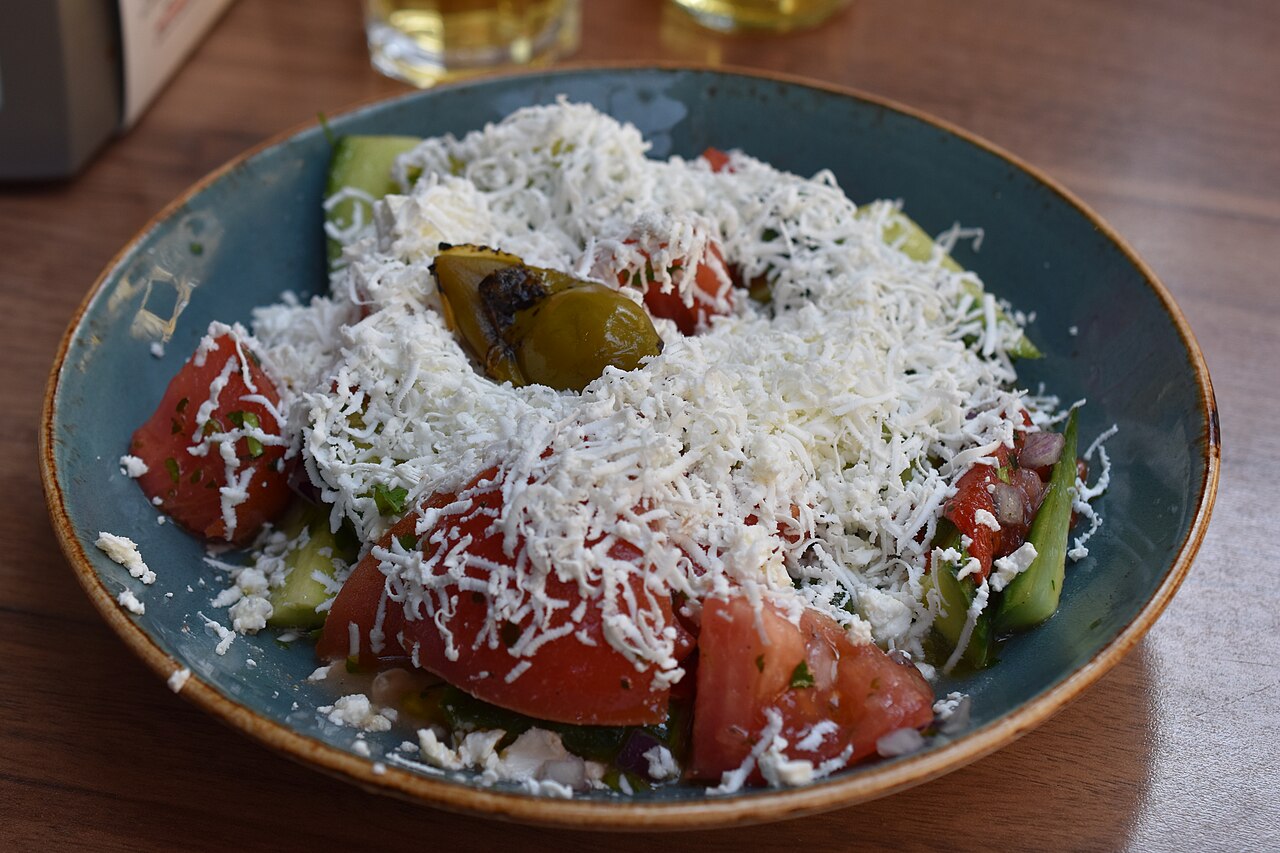 A shopska salad of chopped tomato and cucumber under grated white cheese