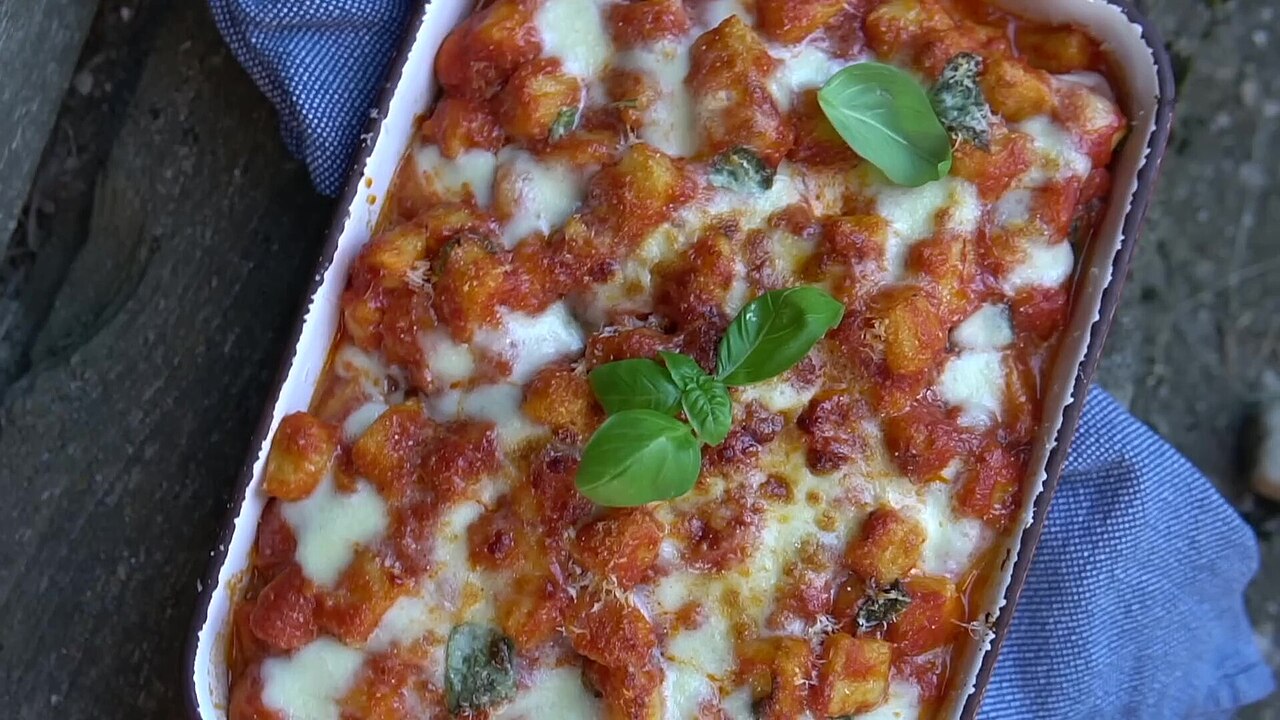 A baking dish of gnocchi alla sorrentina, gnocchi in tomato sauce under melted mozzarella and basil