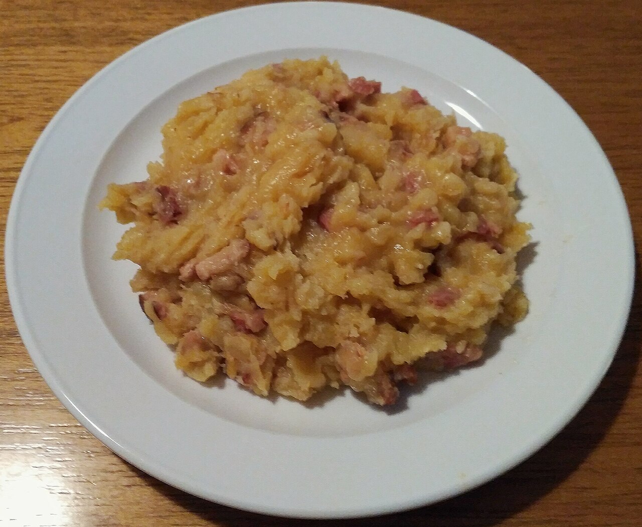 A white plate of mulgipuder, Estonian potato and barley porridge with bacon pieces
