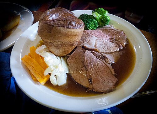 A plate of roast lamb with a Yorkshire pudding in gravy