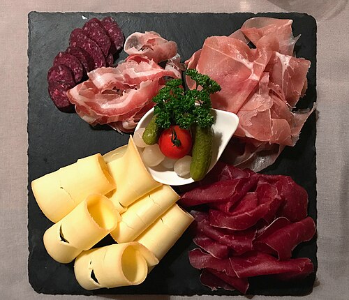 A Valais plate in a Zermatt restaurant, with raclette cheese beside several kinds of cured meat