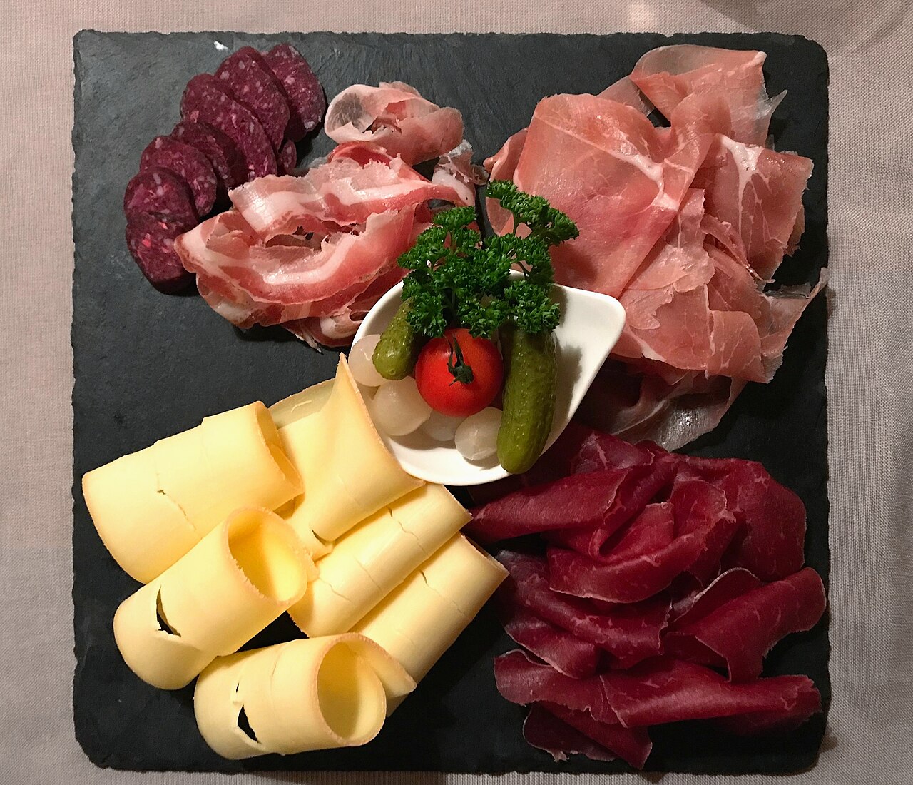 A Valais plate in a Zermatt restaurant, with raclette cheese beside several kinds of cured meat